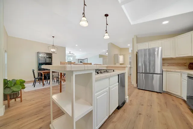 a kitchen with stainless steel appliances kitchen island granite countertop a table chairs and a refrigerator