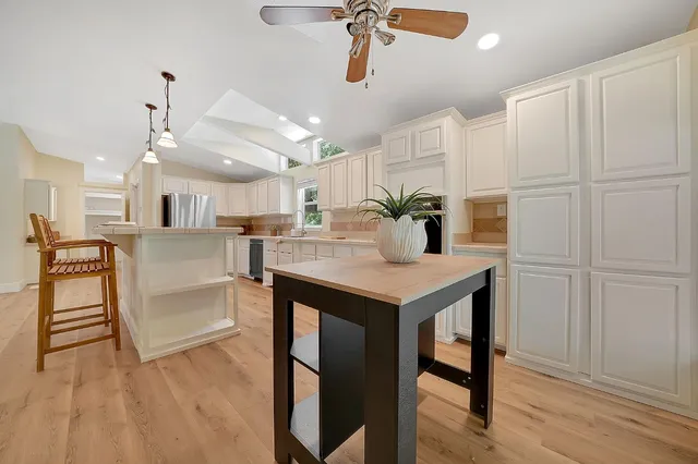 a kitchen with kitchen island white cabinets and stainless steel appliances