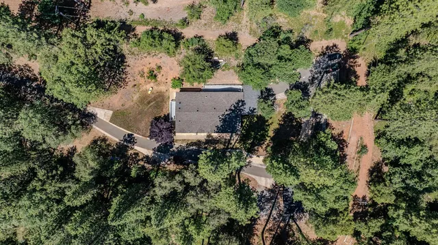 an aerial view of residential house with outdoor space and trees all around