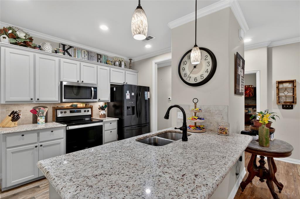 701 West Lamberth Road Sherman, TX 75092 - Photo 13 of 37 Kitchen featuring light-toned cabinetry with dark hardware, speckled countertops, stainless steel microwave, black range, and black refrigerator