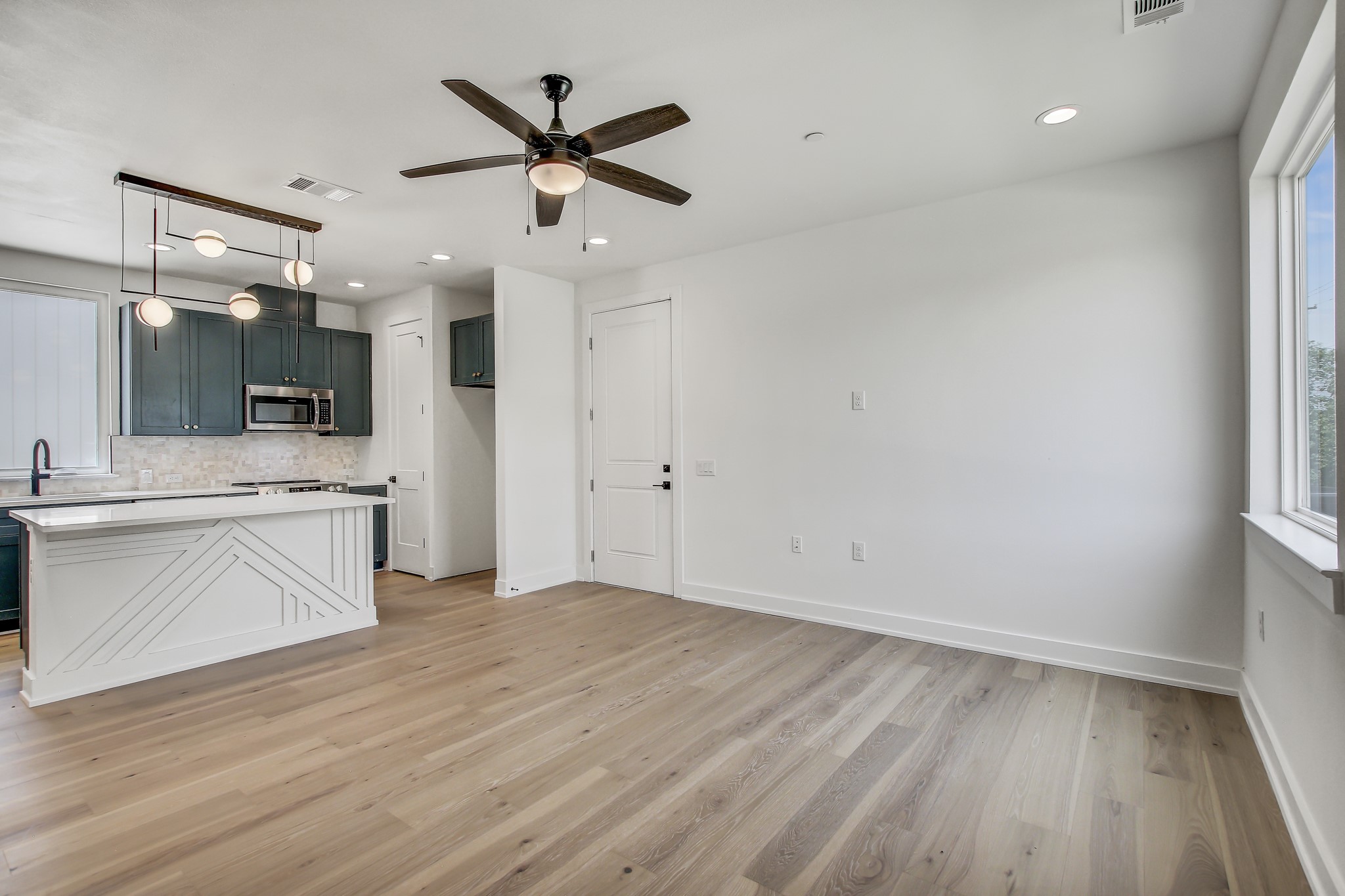 4127 East 12th Street, Unit 5 Austin, TX 78721 - Photo 4 of 33 Kitchen with stainless steel microwave, backsplash, a ceiling fan, light countertops, and baseboards