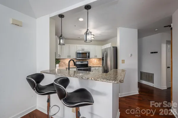 a kitchen with kitchen island granite countertop a sink cabinets and stainless steel appliances