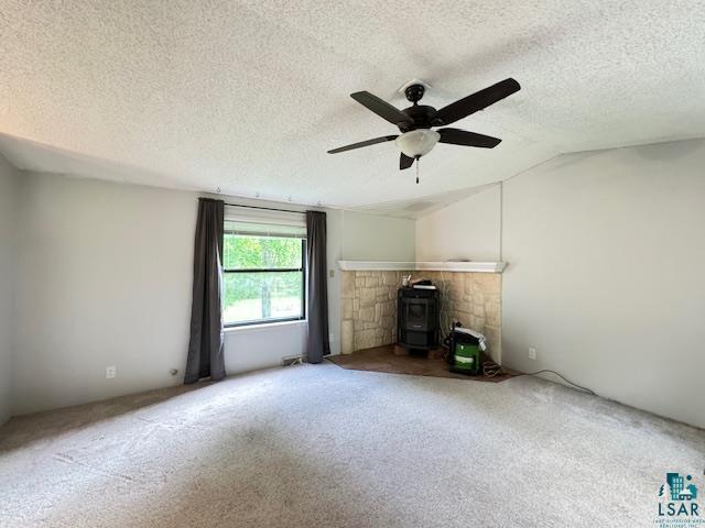12 West St Louis River Road Esko, MN 55733 - Photo 10 of 20 Unfurnished living room with ceiling fan, vaulted ceiling, carpet floors, and a wood stove
