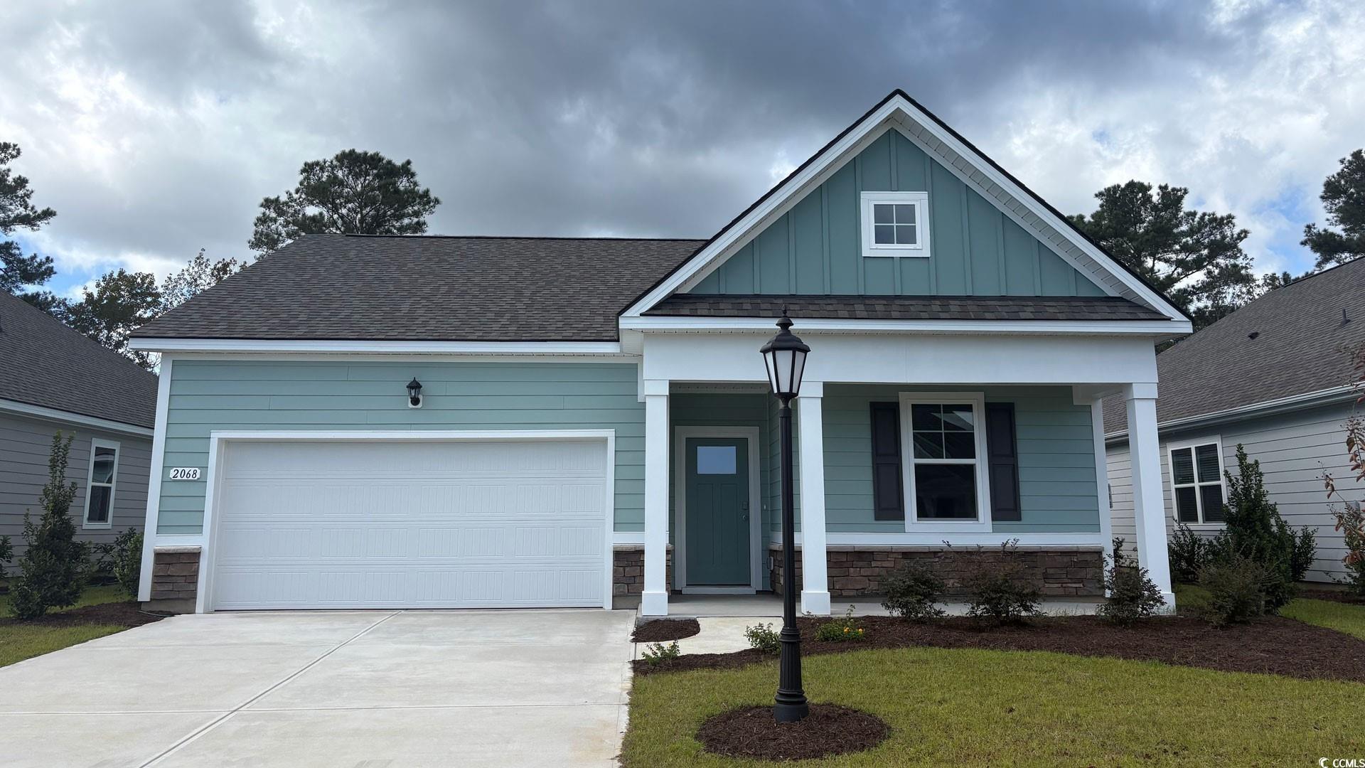 View of front of house with a porch, board and batten siding, concrete driveway, a garage, and a front lawn