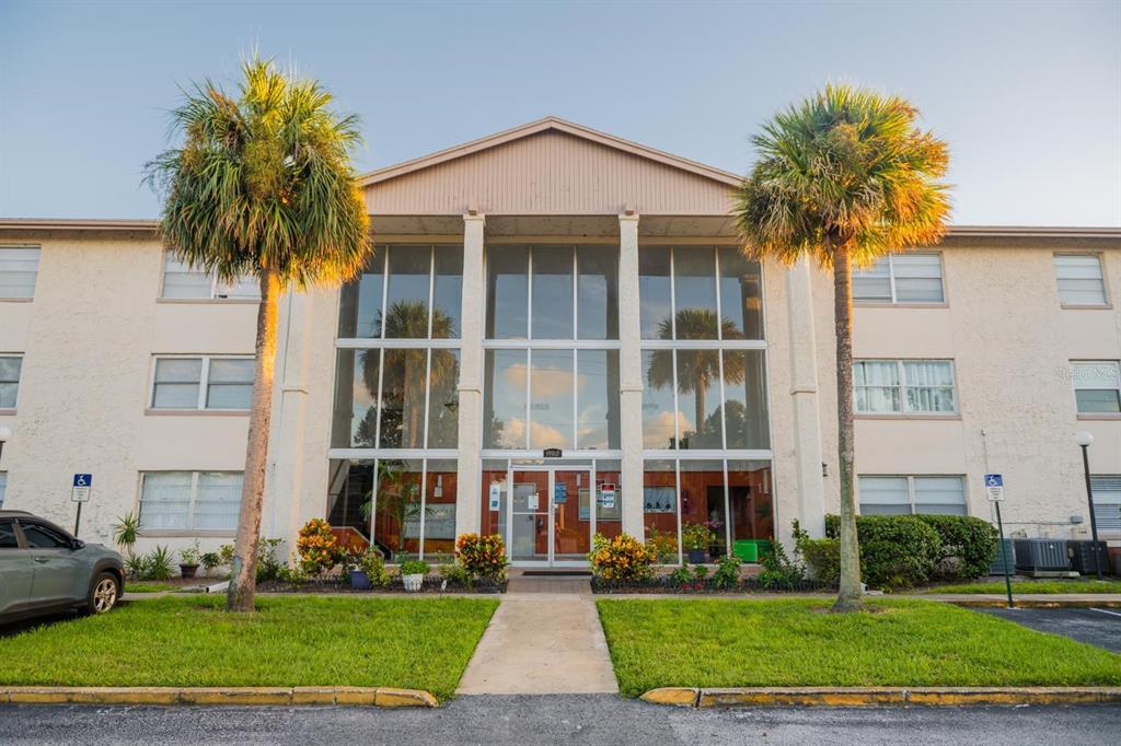 a front view of multi story residential apartment building with yard and green space