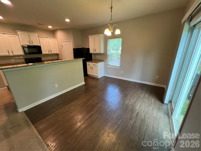 a view of kitchen with granite countertop refrigerator stove microwave and cabinets