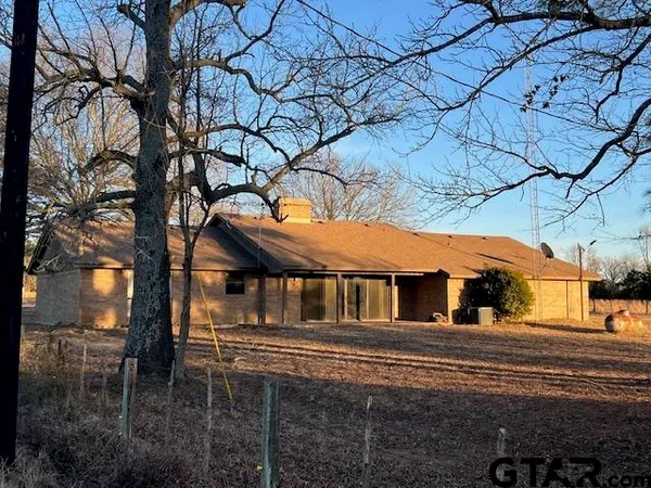 a front view of a house with large trees