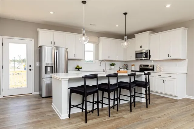 a kitchen with stainless steel appliances granite countertop a dining table chairs refrigerator and microwave