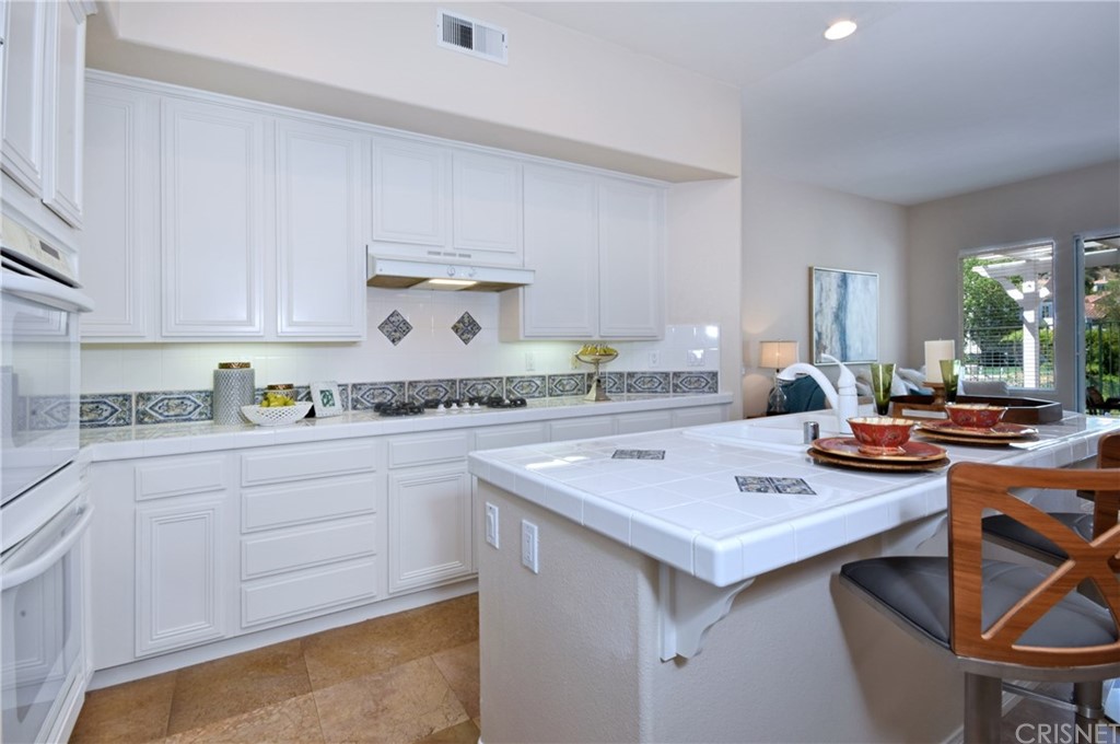 3619 Cll Joaquin Calabasas, CA 91302 - Photo 25 of 42 a kitchen with a stove a sink dishwasher and white cabinets with wooden floor