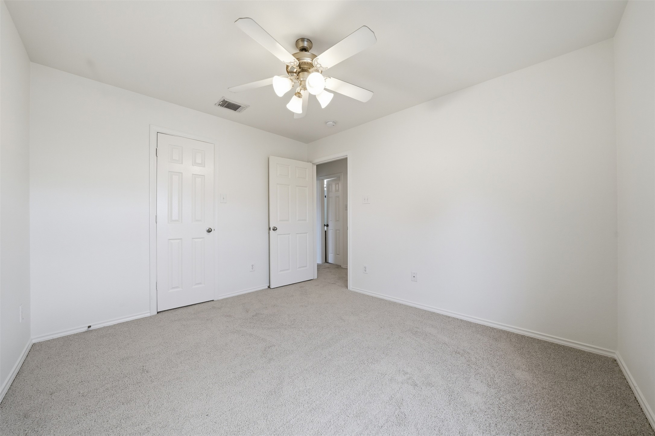 118 Invierno Street Kyle, TX 78640 - Photo 24 of 37 A well-lit bedroom with fresh carpet and a ceiling fan offers a comfortable living space.