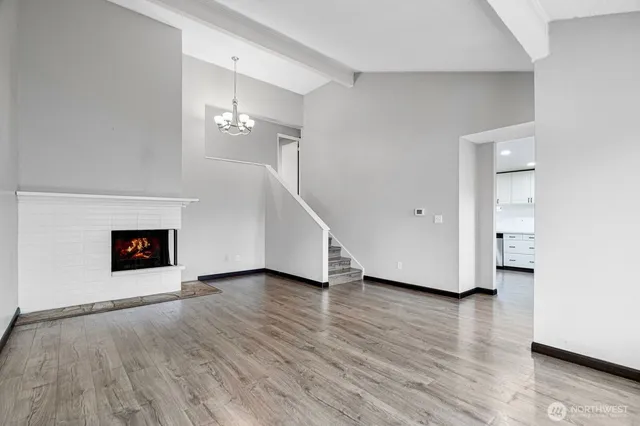 a view of an empty room with wooden floor and a fireplace