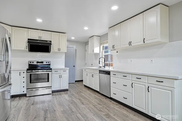 a kitchen with granite countertop a sink cabinets and stainless steel appliances