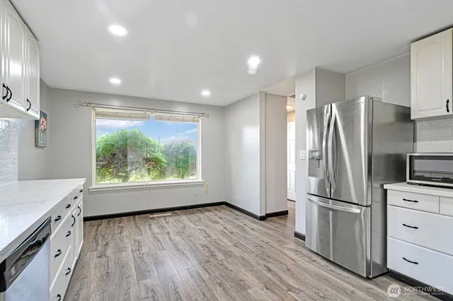 a kitchen with stainless steel appliances a refrigerator sink and wooden floor