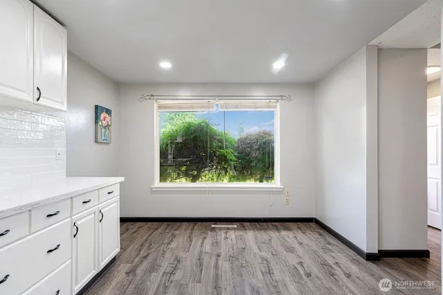 a view of an empty room with a window and wooden floor
