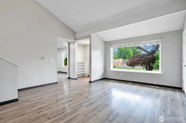 an empty room with wooden floor and windows
