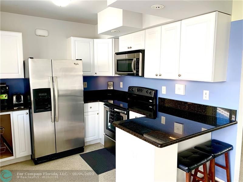 a kitchen with stainless steel appliances granite countertop a sink a stove a refrigerator a washer and dryer