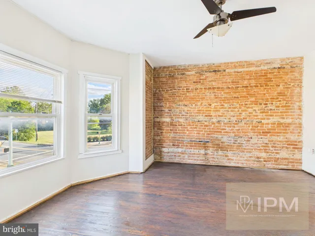 a view of an empty room with window and wooden floor