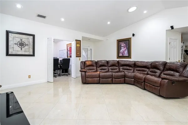 a living room with furniture kitchen view and a chandelier