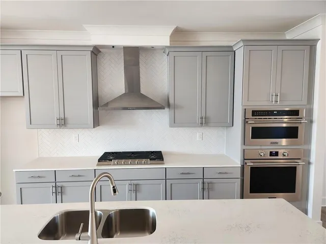 a kitchen with stainless steel appliances granite countertop a stove top oven a sink dishwasher a refrigerator and white cabinets with wooden floor