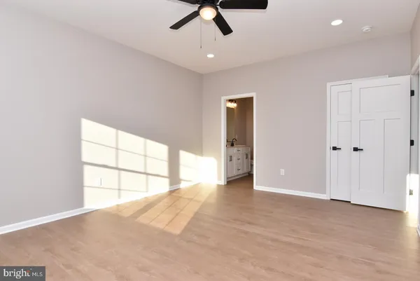 an empty room with chandelier fan and windows