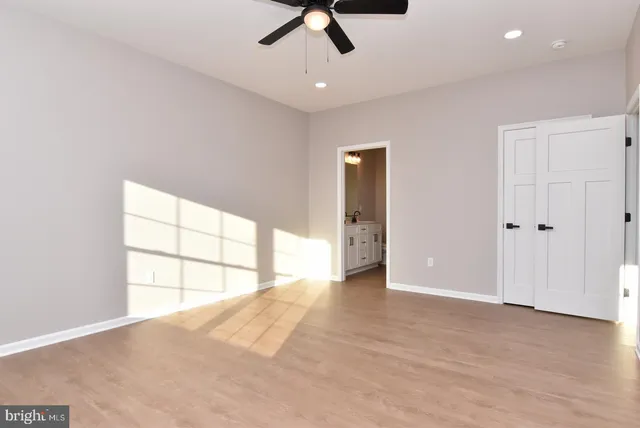 an empty room with chandelier fan and windows