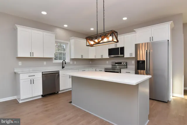 a kitchen with kitchen island a white cabinets and stainless steel appliances