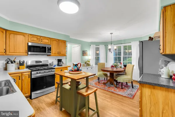 a kitchen with stainless steel appliances granite countertop a stove top oven a sink dishwasher a dining table and chairs with wooden floor