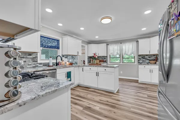 a kitchen with stainless steel appliances granite countertop a stove top oven a sink and a refrigerator