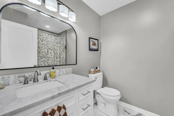 a bathroom with a granite countertop sink mirror vanity and toilet