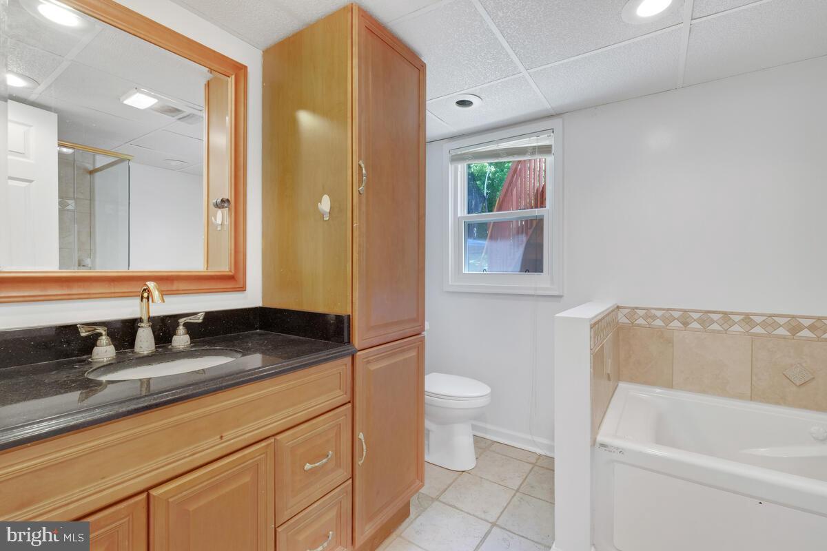 12900 Glynis Road Clinton, MD 20735 - Photo 23 of 38 a bathroom with a granite countertop sink a toilet and bathtub