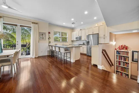 a living room with stainless steel appliances furniture wooden floor and a kitchen view