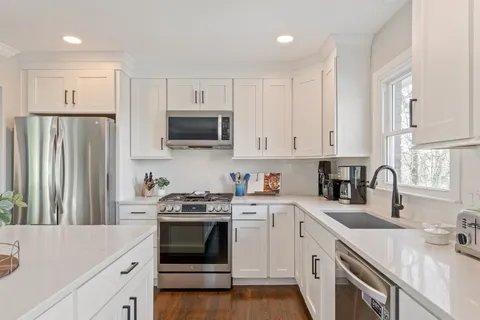 a kitchen with a table chairs wooden floors and white stainless steel appliances