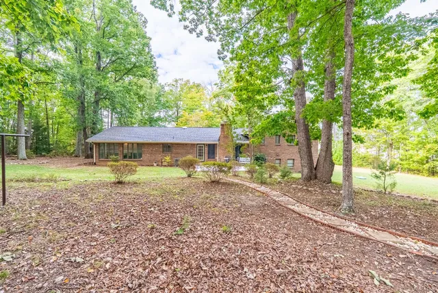 a view of a house with a yard and large tree