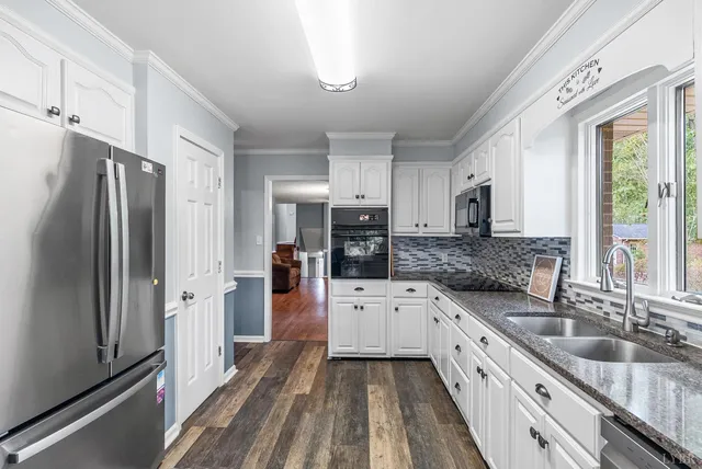 a kitchen with granite countertop a refrigerator sink and white cabinets