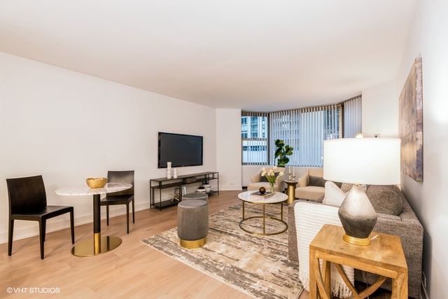 a living room with furniture a flat screen tv and kitchen view