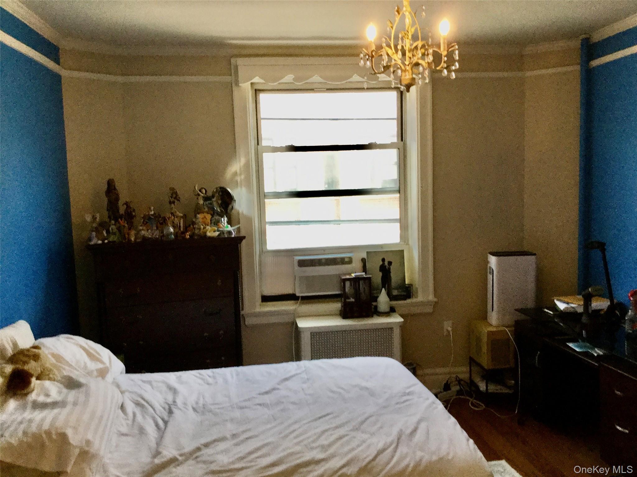 35-20 82nd Street, Unit 31J Queens, NY 11372 - Photo 4 of 10 Bedroom featuring dark wood-style flooring, radiator heating unit, and a chandelier