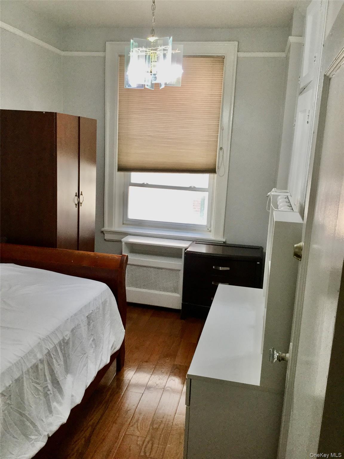 35-20 82nd Street, Unit 31J Queens, NY 11372 - Photo 5 of 10 Bedroom with dark wood-style flooring, radiator, and a chandelier