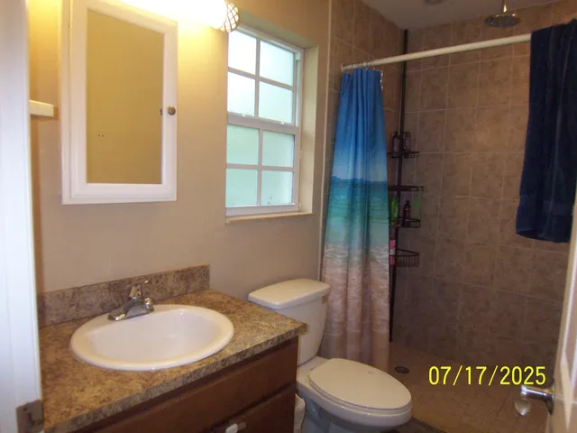 a bathroom with a granite countertop sink toilet a mirror and shower