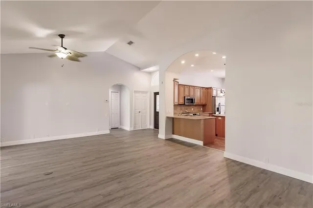 a view of an empty room with kitchen and a window