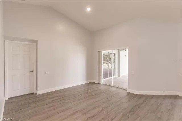 a view of an empty room with wooden floor and a ceiling fan
