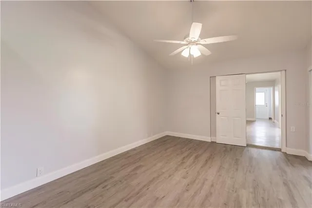 an empty room with wooden floor fan and windows