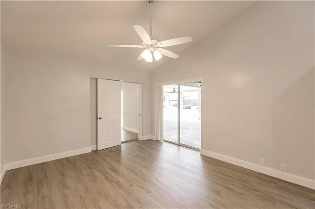 an empty room with wooden floor fan and windows