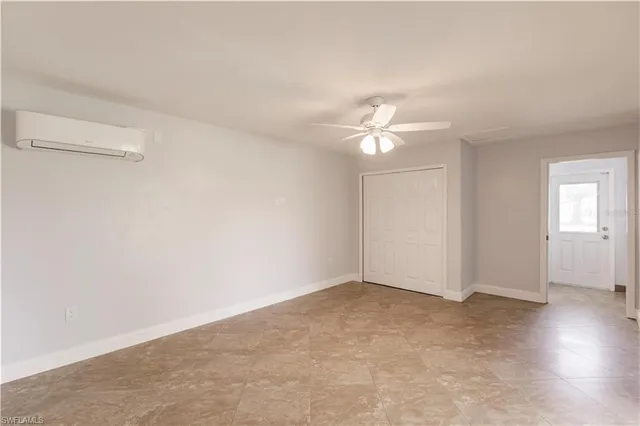 an empty room with chandelier fan and windows