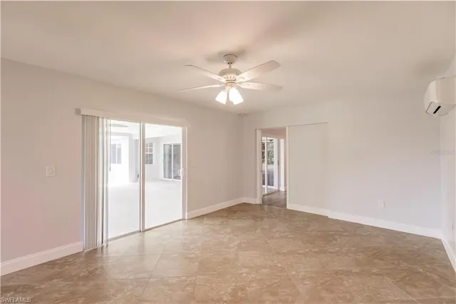 an empty room with wooden floor ceiling fan and windows