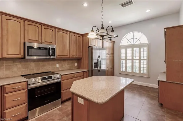 a kitchen with stainless steel appliances granite countertop a stove top oven a sink dishwasher a dining table and chairs with wooden floor