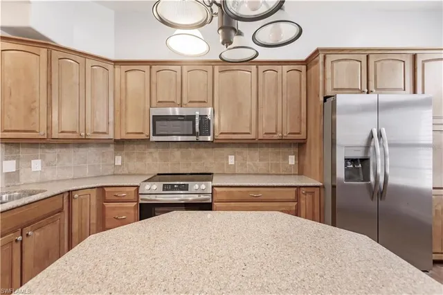 a kitchen with stainless steel appliances granite countertop a refrigerator a stove and a sink with wooden floor