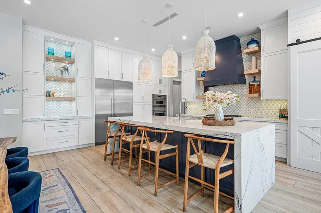 a kitchen with stainless steel appliances kitchen island granite countertop a table chairs and a refrigerator