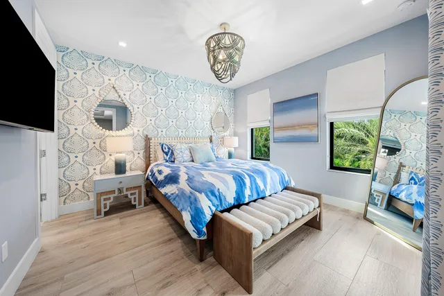 a bedroom with a bed a couch and a flat tv screen on the dresser