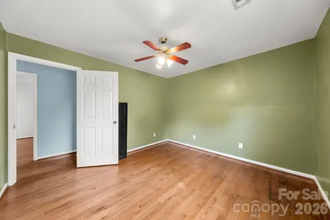 an empty room with wooden floor and fan