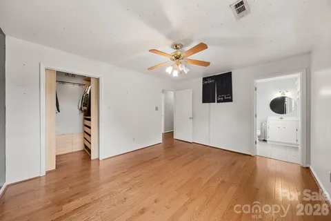 an empty room with wooden floor and a ceiling fan